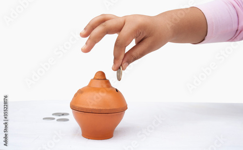 Canvas Print Little Girl putting coin into piggy bank, close-up
