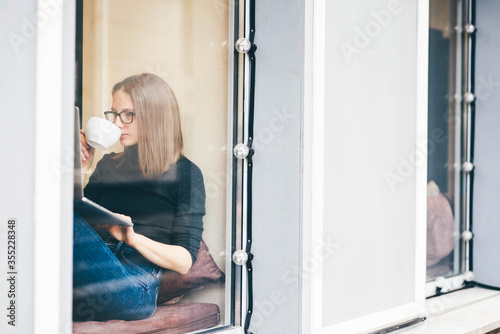 Beautiful woman with cup of coffee using laptop in cafe