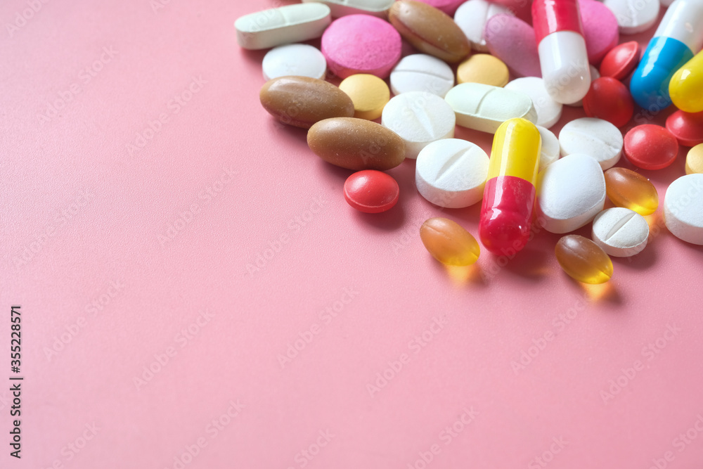 Top view of colorful pills spilling on pink Top view of colorful pills spilling on pink