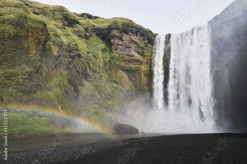 View of a waterfall next to a rainbow in Iceland
