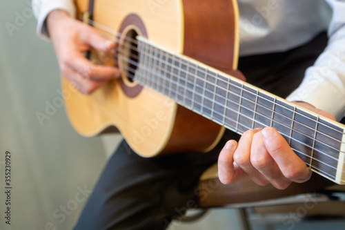 Classical guitar - Guitarist playing acoustic guitar in studio - selective focus close-up of the fingerboard and hand 