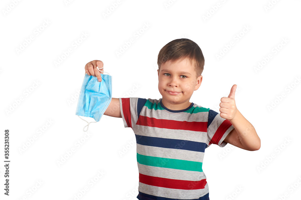 Young smiling boy taking off medical protective mask and shows thumbs up. covid-19 pandemic, self-isolation concept. Quarantine is over concept Young smiling boy taking off medical protective mask and shows thumbs up. covid-19 pandemic, self-isolation concept. Quarantine is over concept