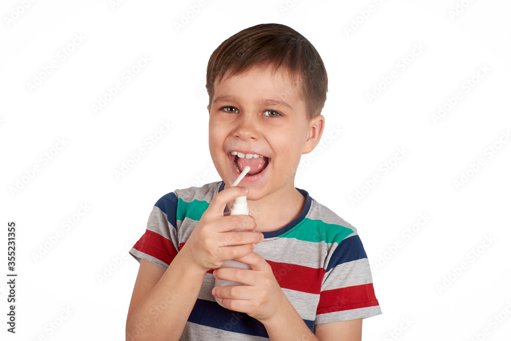 Smiling boy sprays himself mouth with a spray from the pain in her throat. Isolated on a white background. Smiling boy sprays himself mouth with a spray from the pain in her throat. Isolated on a white background.