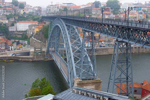 The Dom Luis I Bridge over the Douro River and the colorful houses of Porto Ribeira, traditional facades, old multi-colored houses with red roof tiles on the embankment in the city of Porto, Portugal.