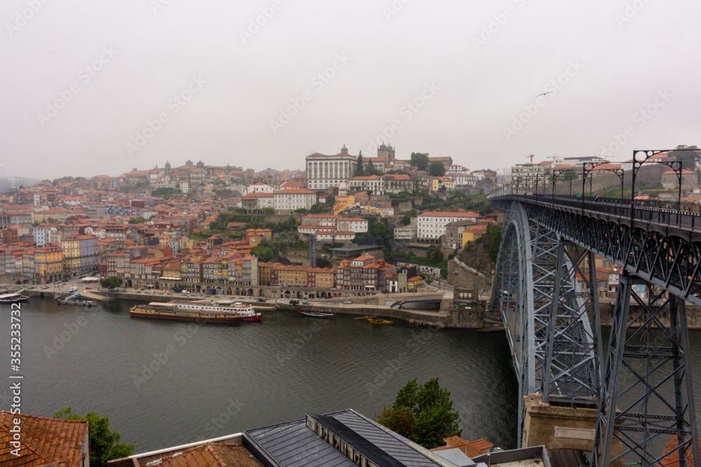 Fototapeta premium The Dom Luis I Bridge over the Douro River and the colorful houses of Porto Ribeira, traditional facades, old multi-colored houses with red roof tiles on the embankment in the city of Porto, Portugal.