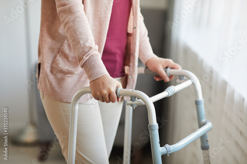 Close-up of senior woman using walker while moving along the room at home photo