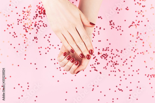 Manicure and nailcare concept. Two woman hands and falling confetti on pink background. Flat-lay, top view. Copy space. photo