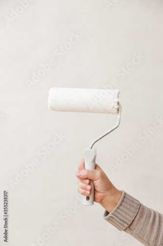 Painting roller in worker's hand. Repair in a room. Painting of walls