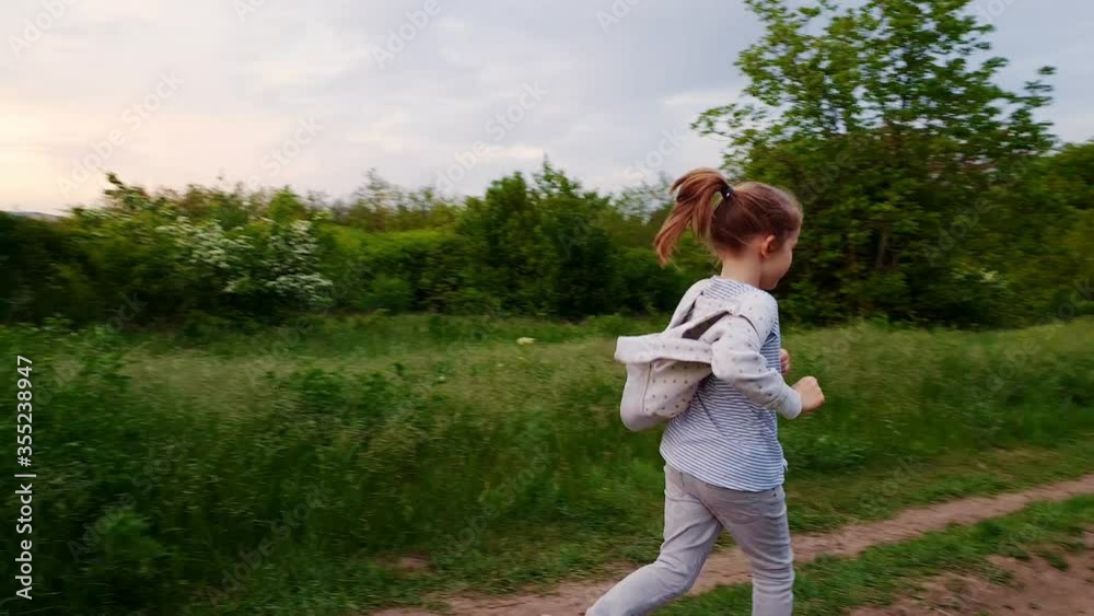 little girl runs on footpath in field. active rest on nature. little girl runs on footpath in field. active rest on nature.