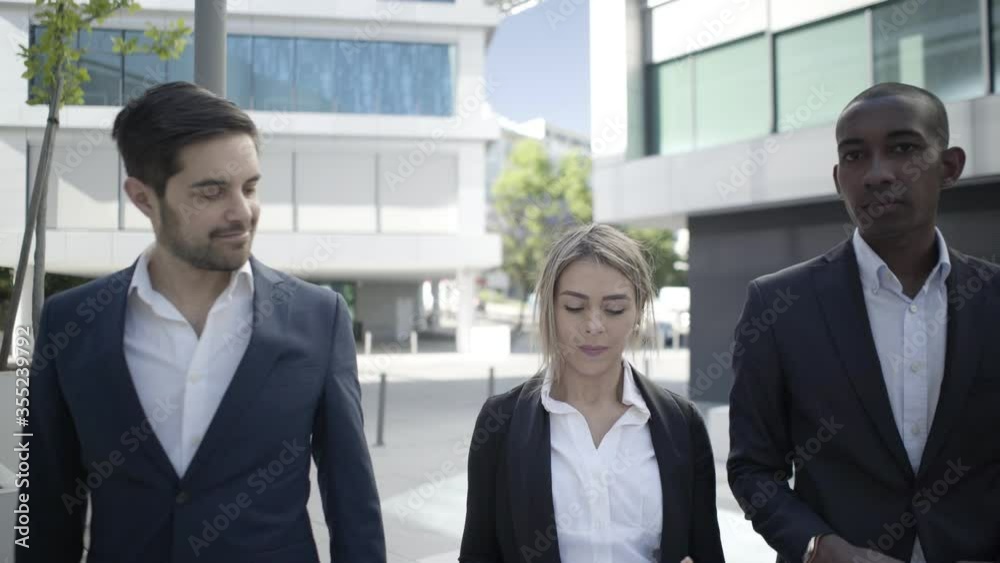 Happy successful colleagues with documents walking outdoors and talking. Front view, medium shot. Business success and teamwork concept Happy successful colleagues with documents walking outdoors and talking. Front view, medium shot. Business success and teamwork concept