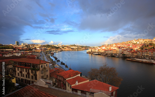 Morning in Porto Portugal: Douro river and banks of Ribeira district and Vila Nova de Gaia, on an overcast day, with a patch of clear blue sky in the sunlit distance.