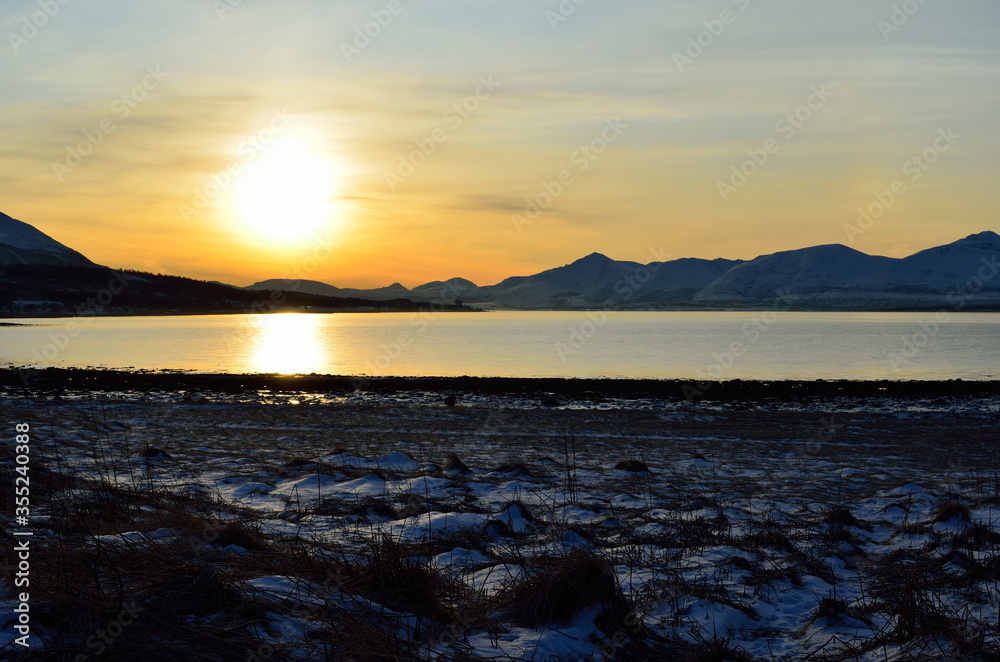 golden sunrise sky over snowy mountain, fjord and field