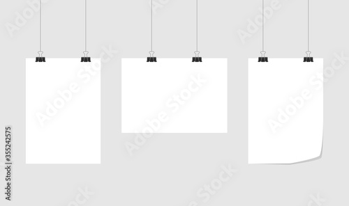 Set binder clips on a piece of paper. Clerical clothespin isolated on gray background. Vector EPS 10