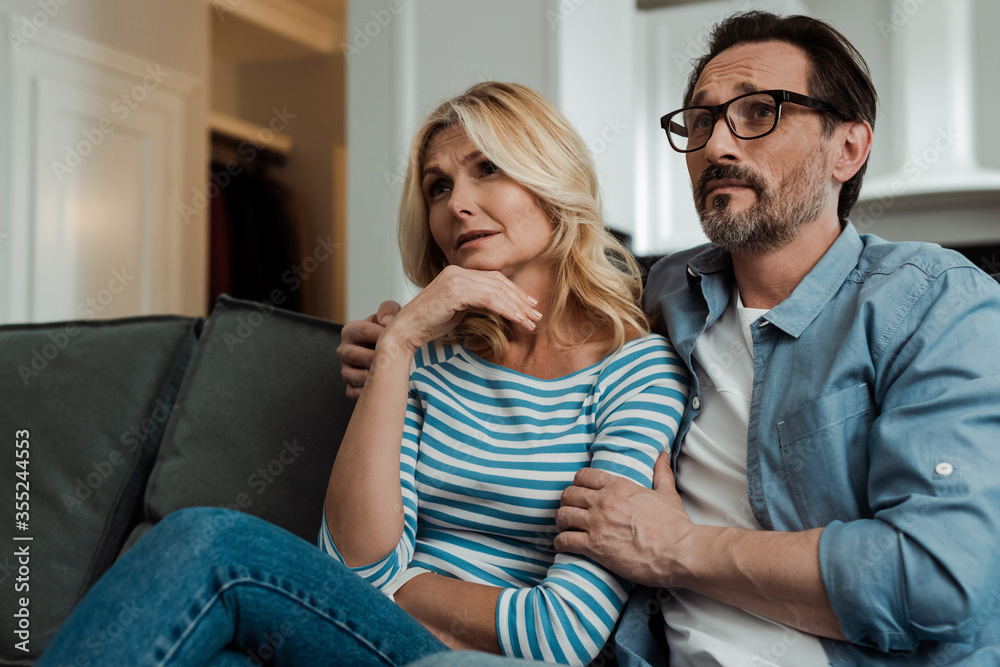 Handsome man embracing wife on couch in living room Handsome man embracing wife on couch in living room