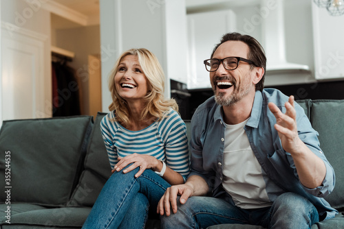 Mature couple laughing while sitting on couch