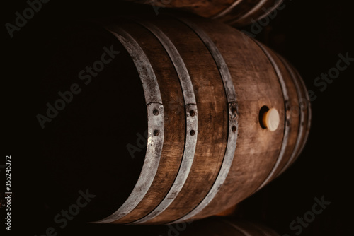 Vintage old oak barrels of wine, cognac in the wine dark vaults of the winery. Selective soft focus. Shooting in the dark