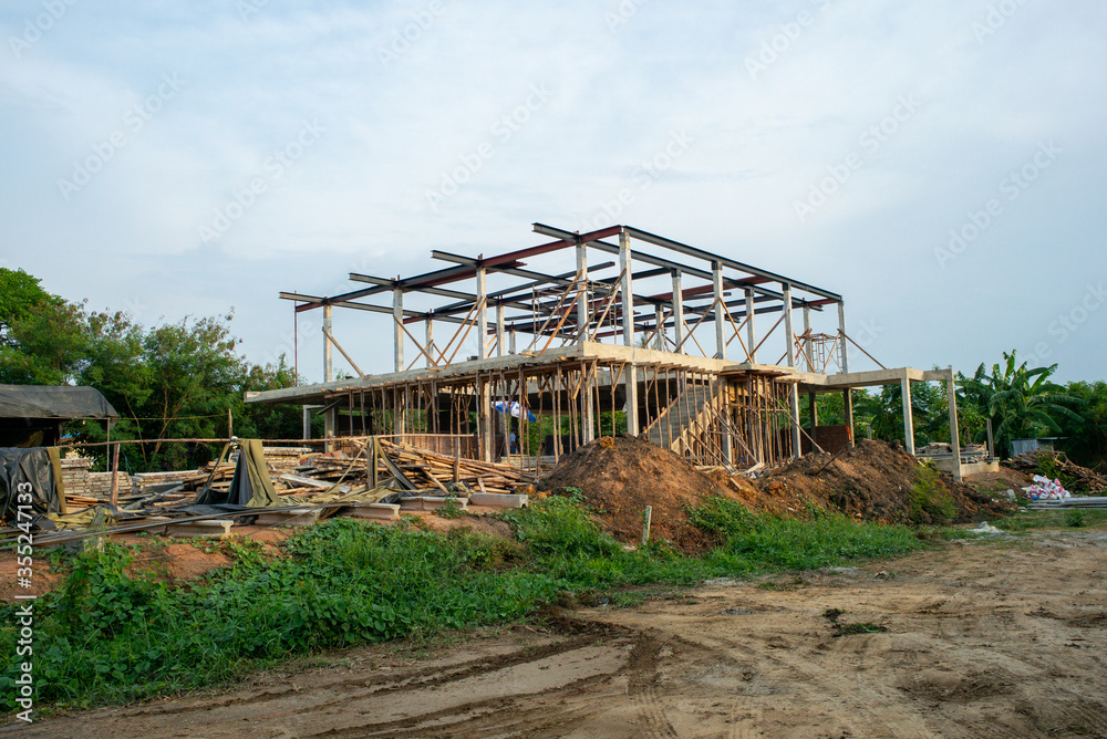 Perspective of house structure under construction at site with blue sky background Perspective of house structure under construction at site with blue sky background