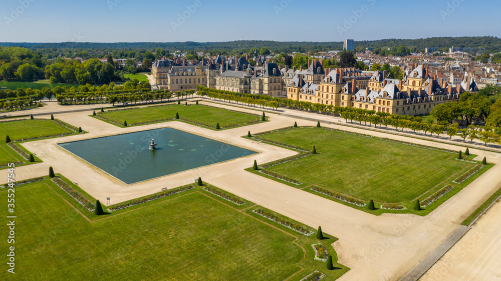 Aerial view of medieval landmark royal hunting castle Fontainbleau near Paris in France and lake with white swans