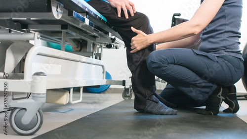 Foto Physiotherapist exercising with disabled person using wheelchair on a therapy table
