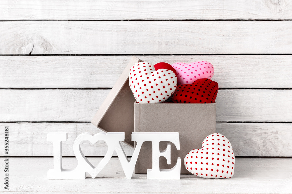 Obraz premium Many Red Heart Shaped with brown gift box and love alphabet over white wood background