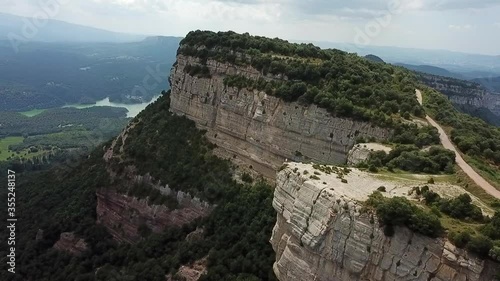 Aerial shot of tourists on rocky cliff against cloudy sky, drone flying backward from rocky mountain during sunny day - Tavertet, Spain photo