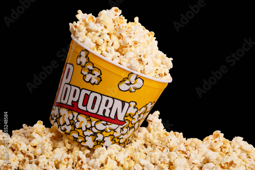 bucket of popcorn on top of a bunch of popcorn on black background