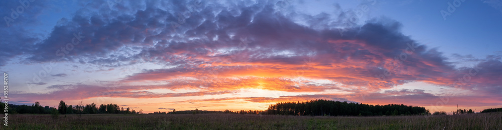 Sunset panoramic landscape of summer field under blue sky with clouds Sunset panoramic landscape of summer field under blue sky with clouds