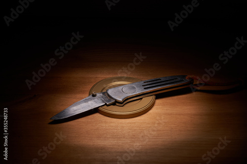 Silver jackknife on a wood table with a top light