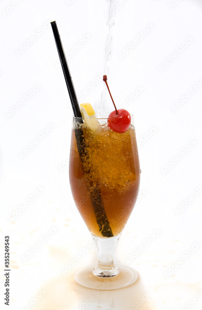 Tonic water pouring into a Cuba LibreRum cocktail, spilling over the glass on white background. Tonic water pouring into a Cuba LibreRum cocktail, spilling over the glass on white background.