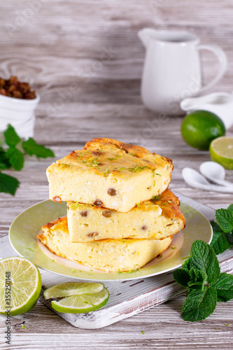 Cottage cheese casserole with raisins, honey and mint, lime slices on a plate on a white table