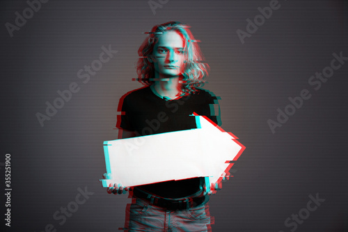 A young guy with long blonde hair and a sad face holds a white arrow pointing to the right with virtual glitch effect.