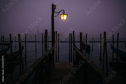 A burning street lamp on the waterfront in the evening in Venice, Italy. 