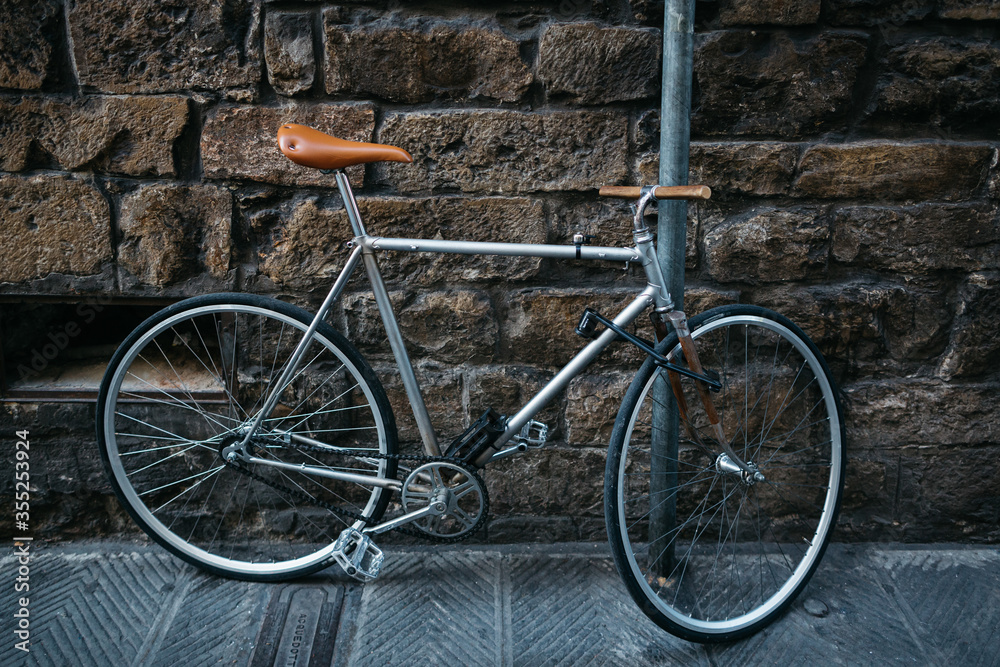 Old retro bike fastened to a pipe against the background of an old stone wall