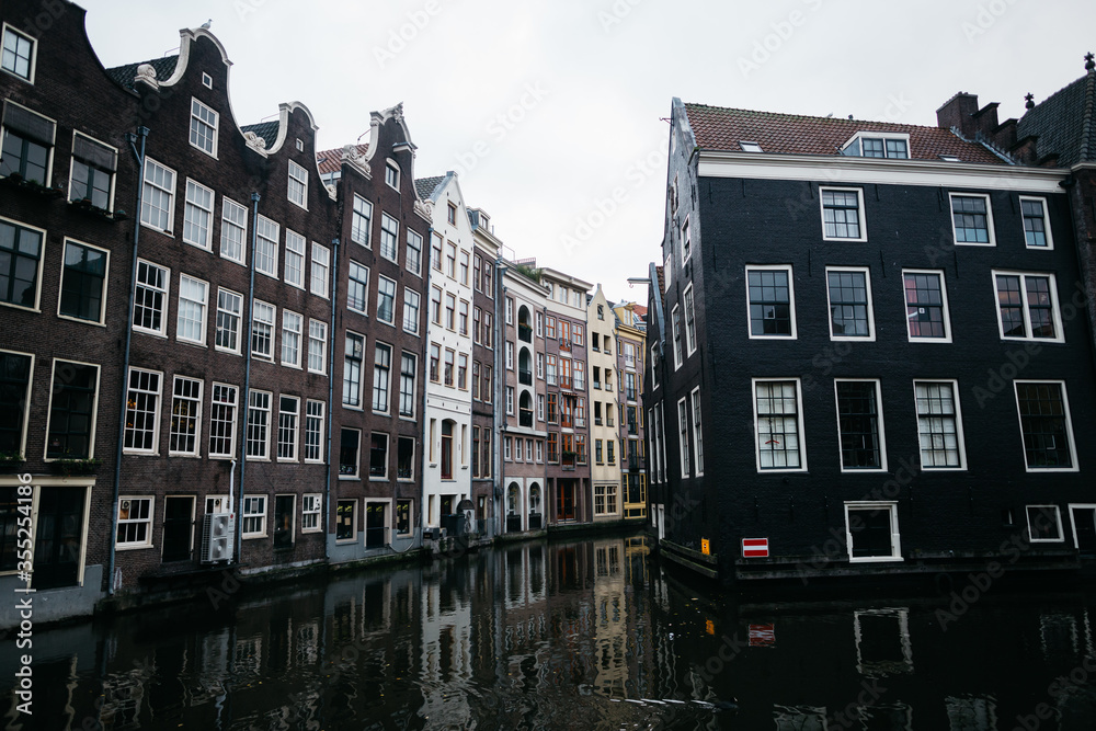 Water canal in Amsterdam without people and boats. Beautiful dark brick buildings in the Netherlands. 