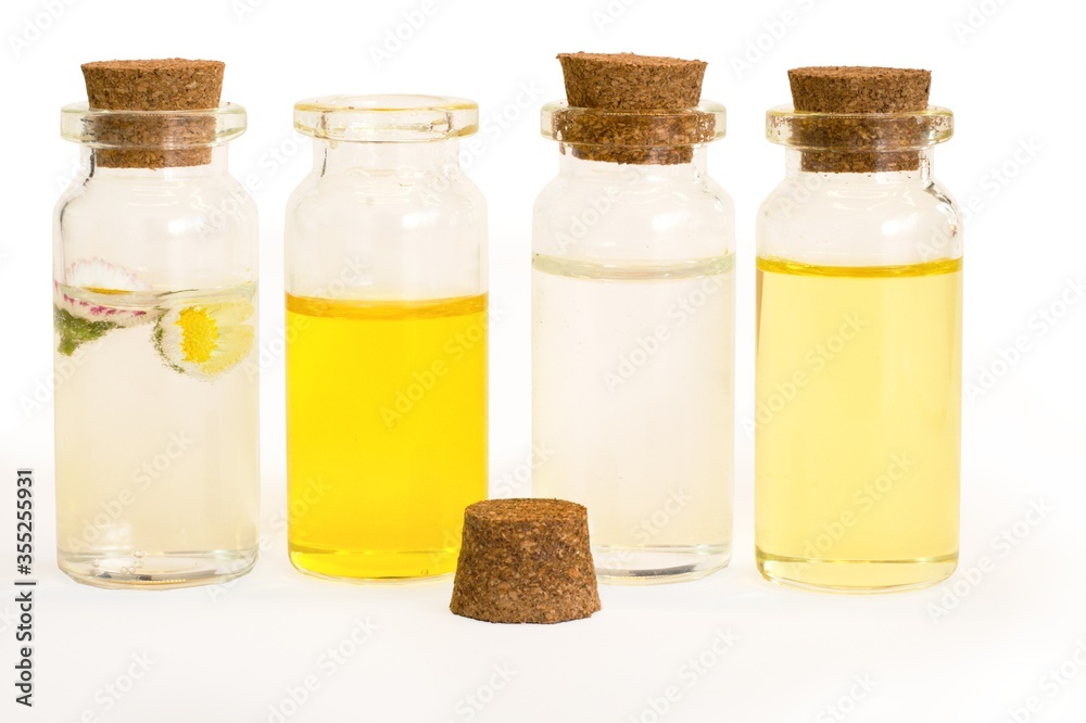 Beautiful photo of small bottles with cork stoppers filled with fantastic fragrant oils, essential oils, rose water and daisies Beautiful photo of small bottles with cork stoppers filled with fantastic fragrant oils, essential oils, rose water and daisies