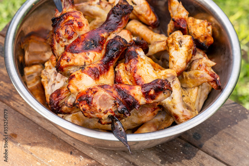 Appetizing grilled chicken legs and wings in a bowl. Close-up.