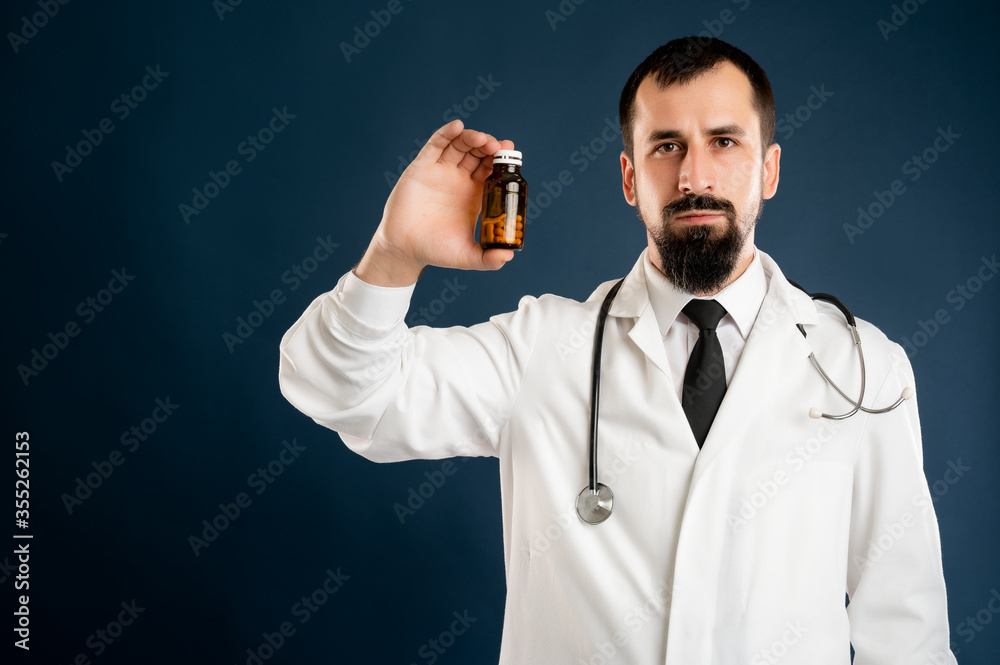 Male doctor with stethoscope in medical uniform holding dose of pills
