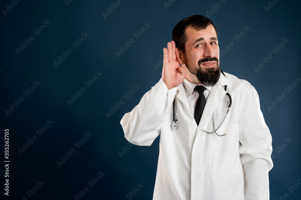 Male doctor with stethoscope in medical uniform paying attention on news or gossip Male doctor with stethoscope in medical uniform paying attention on news or gossip