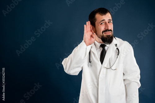 Male doctor with stethoscope in medical uniform paying attention on news or gossip