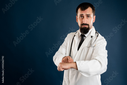 Male doctor with stethoscope in medical uniform showing it's time gesture