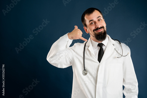 Male doctor with stethoscope in medical uniform showing call me gesture