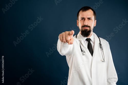Male doctor with stethoscope in medical uniform pointing her finger and smile
