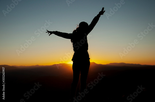 Woman, power, and victory concept.. Silhouette of Woman open arm under sunset. Silhouette of free woman enjoying freedom feeling happy at sunset. relaxing woman in pure happiness. 