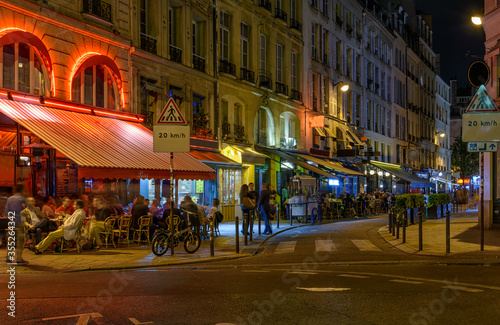 Night view of cozy street with tables of cafe in Paris, France