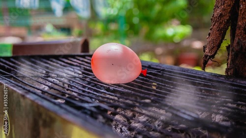 Cinemagraph of smoke emitted from a hot BBQ grill with a water balloon placed on it. Close up, loop with selective focus.