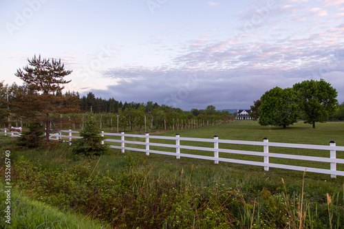 Large fenced country property with rows of cultivated fruit trees headed by wooden signs for the different varieties seen during a spring morning, Saint-Antoine-de-Tilly, Quebec, Canada