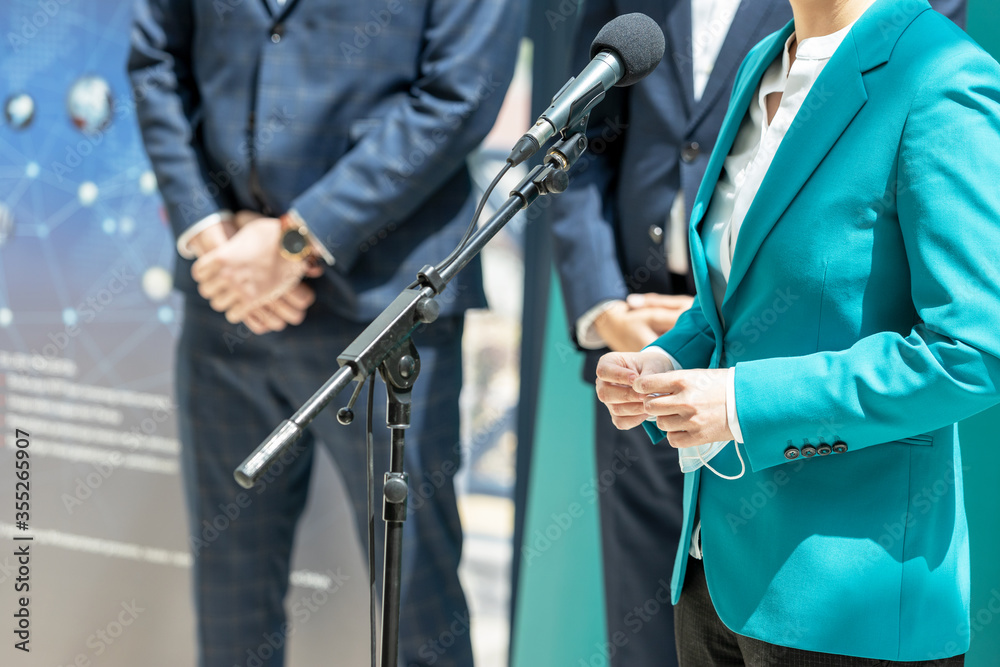 Business woman or female politician is giving a speech at media event - obrazy, fototapety, plakaty 