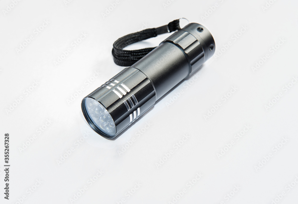Kuala Lumpur, Malaysia - May 11, 2020 : Black metallic with white strips mini flashlight or torch on white background. Kuala Lumpur, Malaysia - May 11, 2020 : Black metallic with white strips mini flashlight or torch on white background.