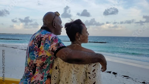 Beautiful Black African American married couple spends romantic evening at tropical island beach sunset in love / kiss scene in Caribbean