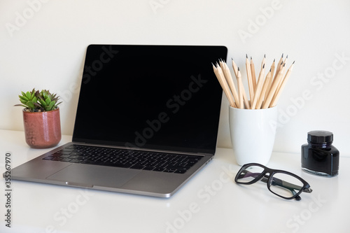 Office desk table with supplies. Top view. Copy space for text. Laptop,  pensils, glass,  flower.